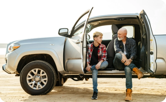 Parent and teen sitting by car discussing driving